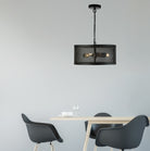 A black metal mesh pendant light hangs above a minimalist dining table with two chairs.