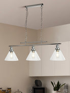 Linear light fixture with three clear glass cone shades in a modern kitchen setting.