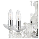 Close-up of two lit candle-style bulbs on the clear glass chandelier with crystal details.