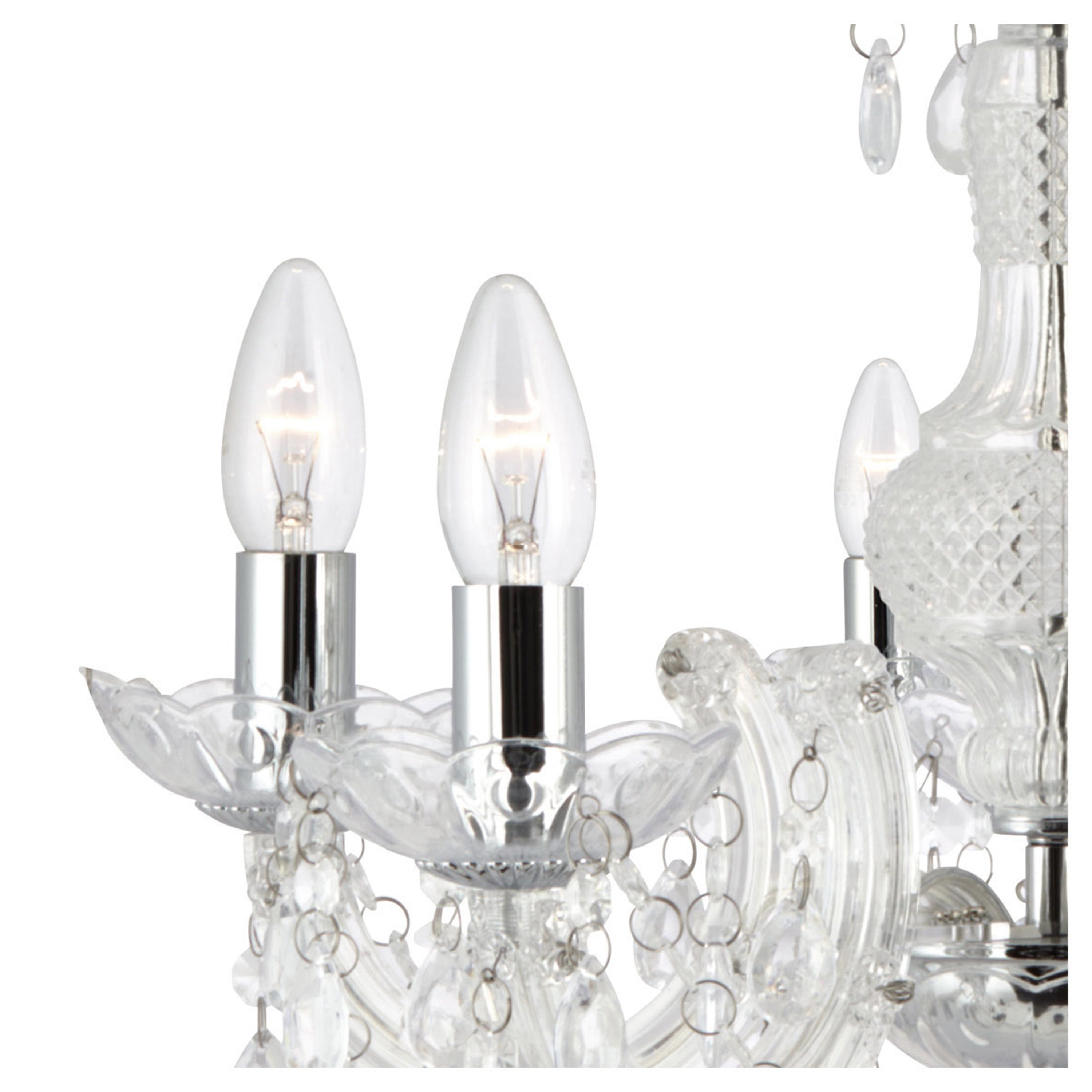 Close-up of two lit candle-style bulbs on the clear glass chandelier with crystal details.