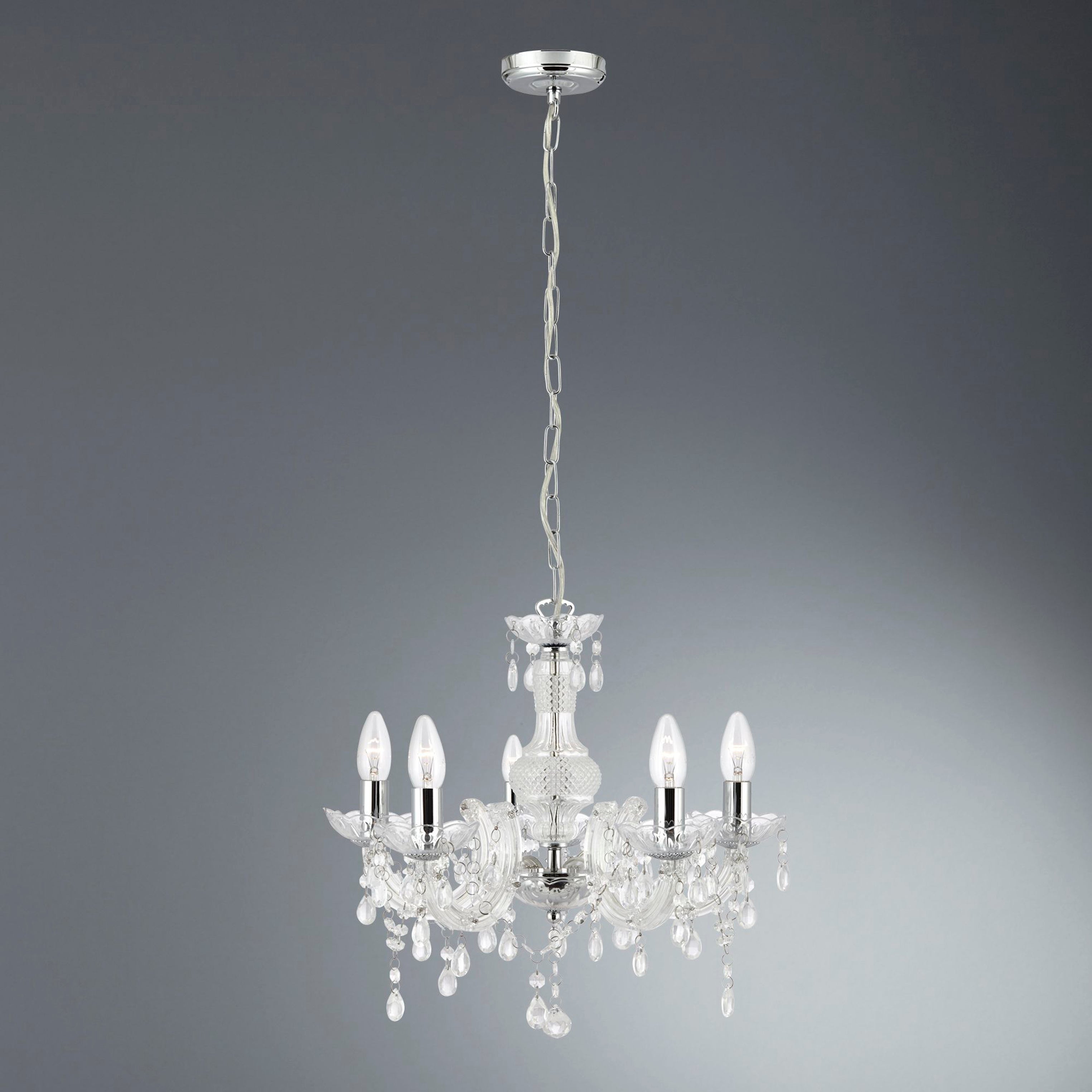 A clear glass chandelier with five lit candle-style bulbs, suspended against a grey background.