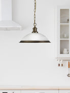 The Antique Brass Pendant Light hanging in a modern white kitchen.