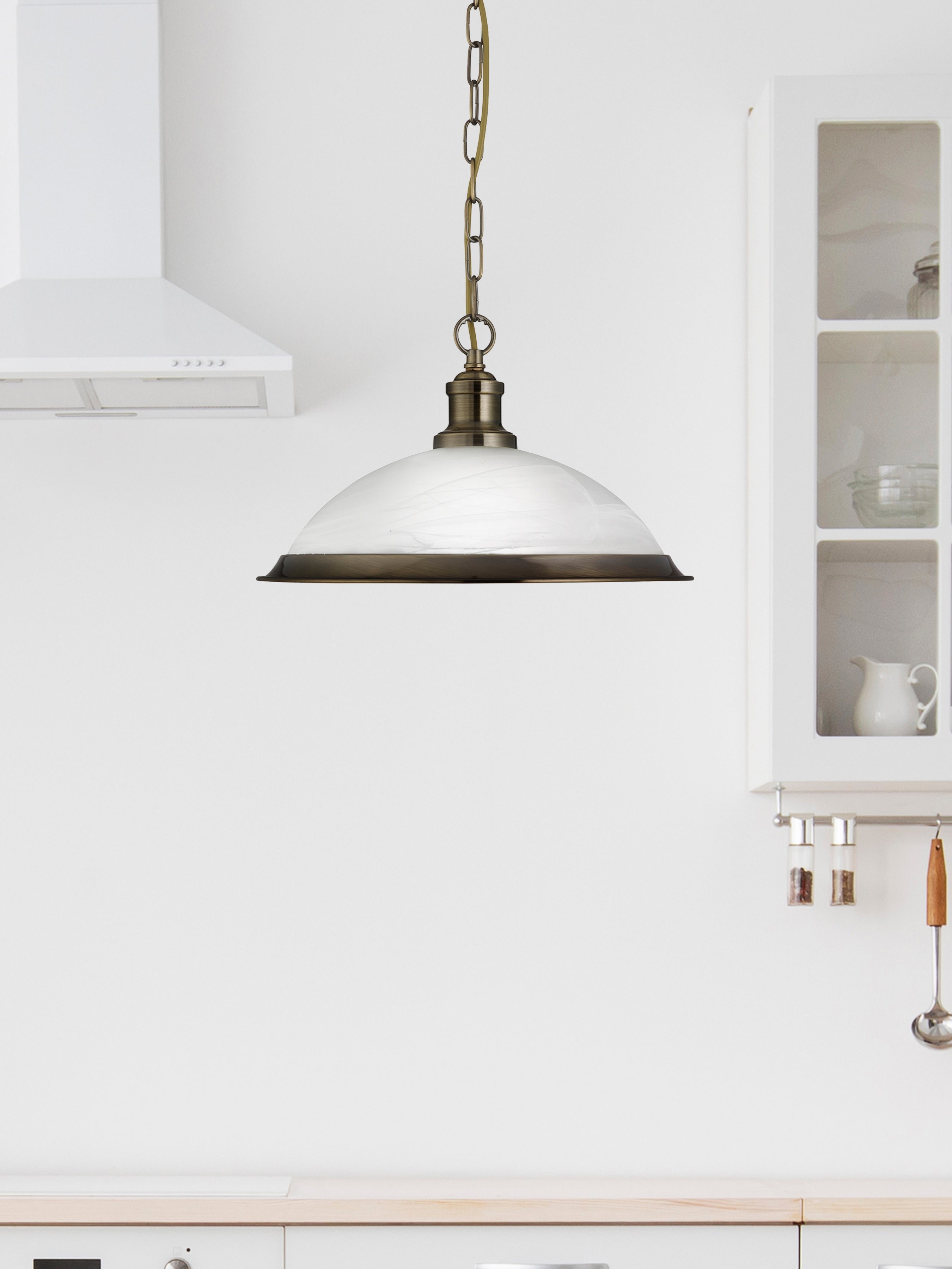 The Antique Brass Pendant Light hanging in a modern white kitchen.