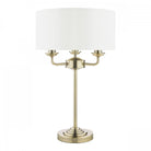 Elegant brass table lamp featuring a white fabric drum shade, ideal for ambient lighting.