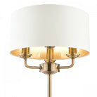 Close-up of the brass fixture and white shade of a sophisticated table lamp.