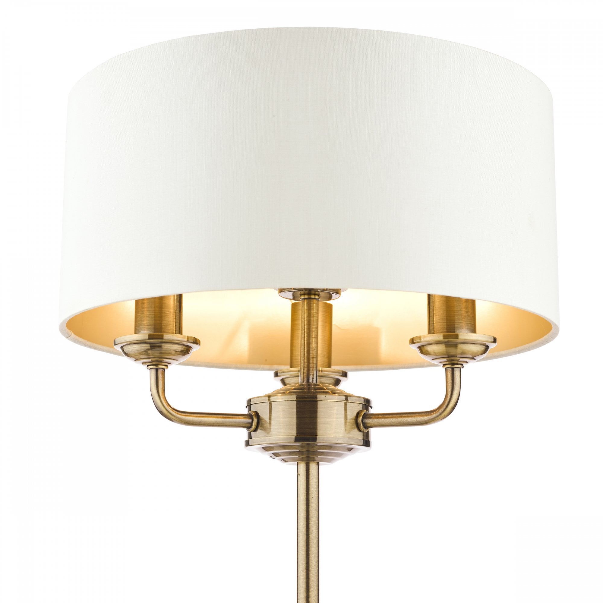 Close-up of the brass fixture and white shade of a sophisticated table lamp.