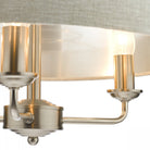 A close-up of a cream drum shade chandelier showing two illuminated candle-style bulbs.