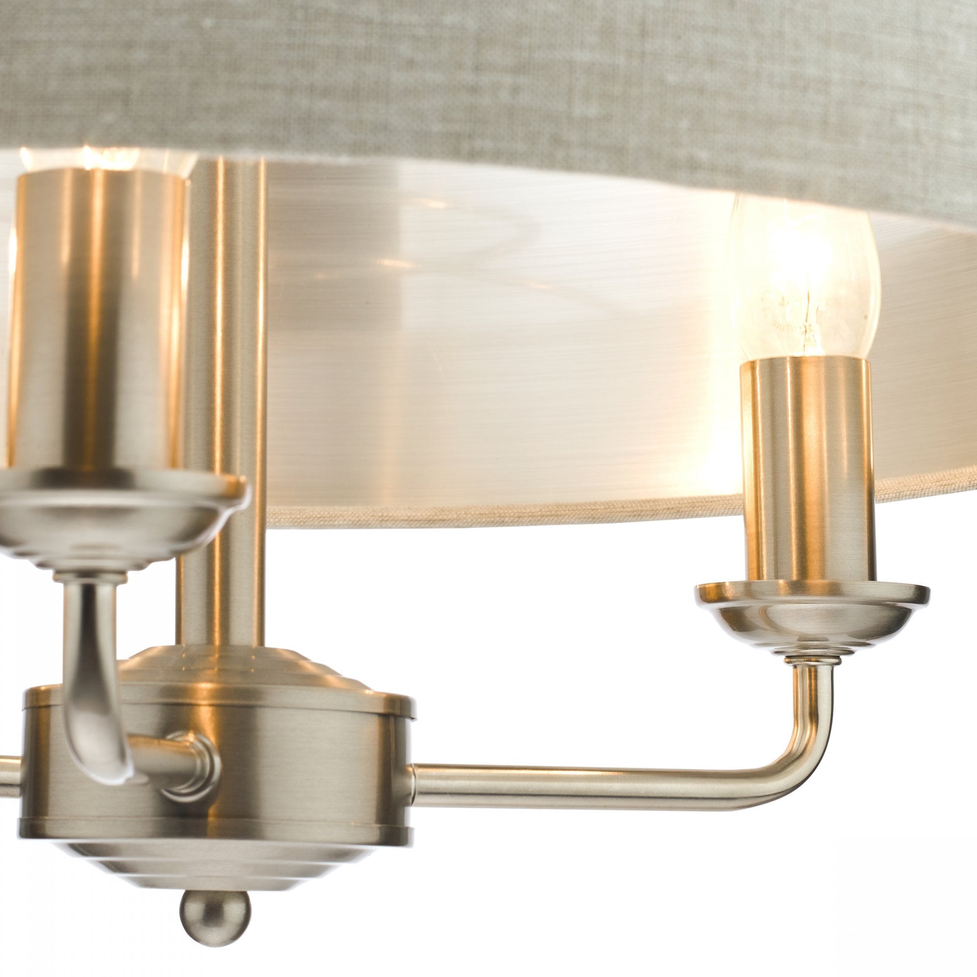 A close-up of a cream drum shade chandelier showing two illuminated candle-style bulbs.