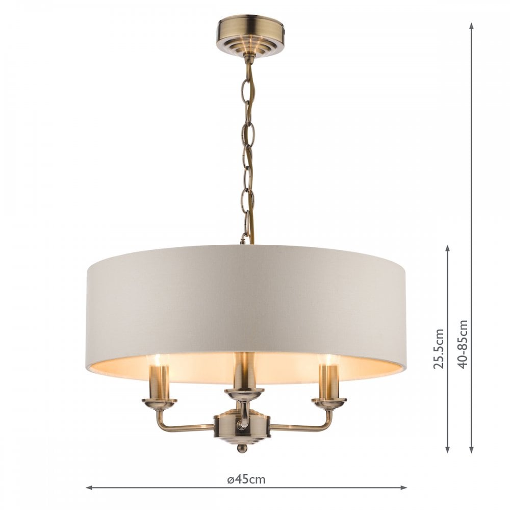 A brass three-arm pendant light with a white drum shade and dimensions labeled.
