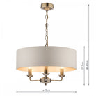 A brass three-arm pendant light with a white drum shade and dimensions labeled.