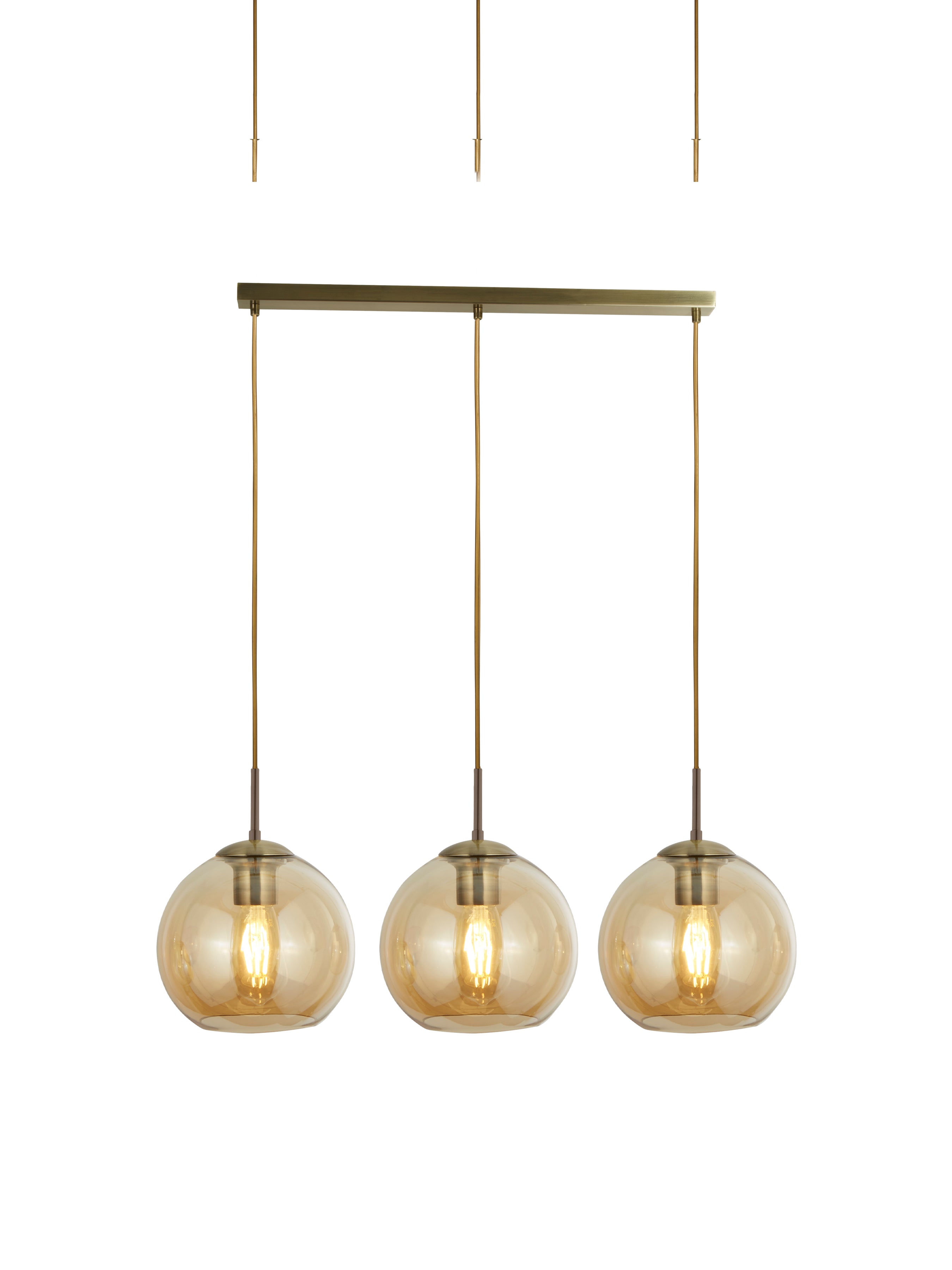 A close-up of three amber glass globe pendant lights hanging from a brass bar.