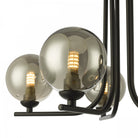 A close-up of a smoked glass orb light on a black ceiling fixture, displaying the bulb.