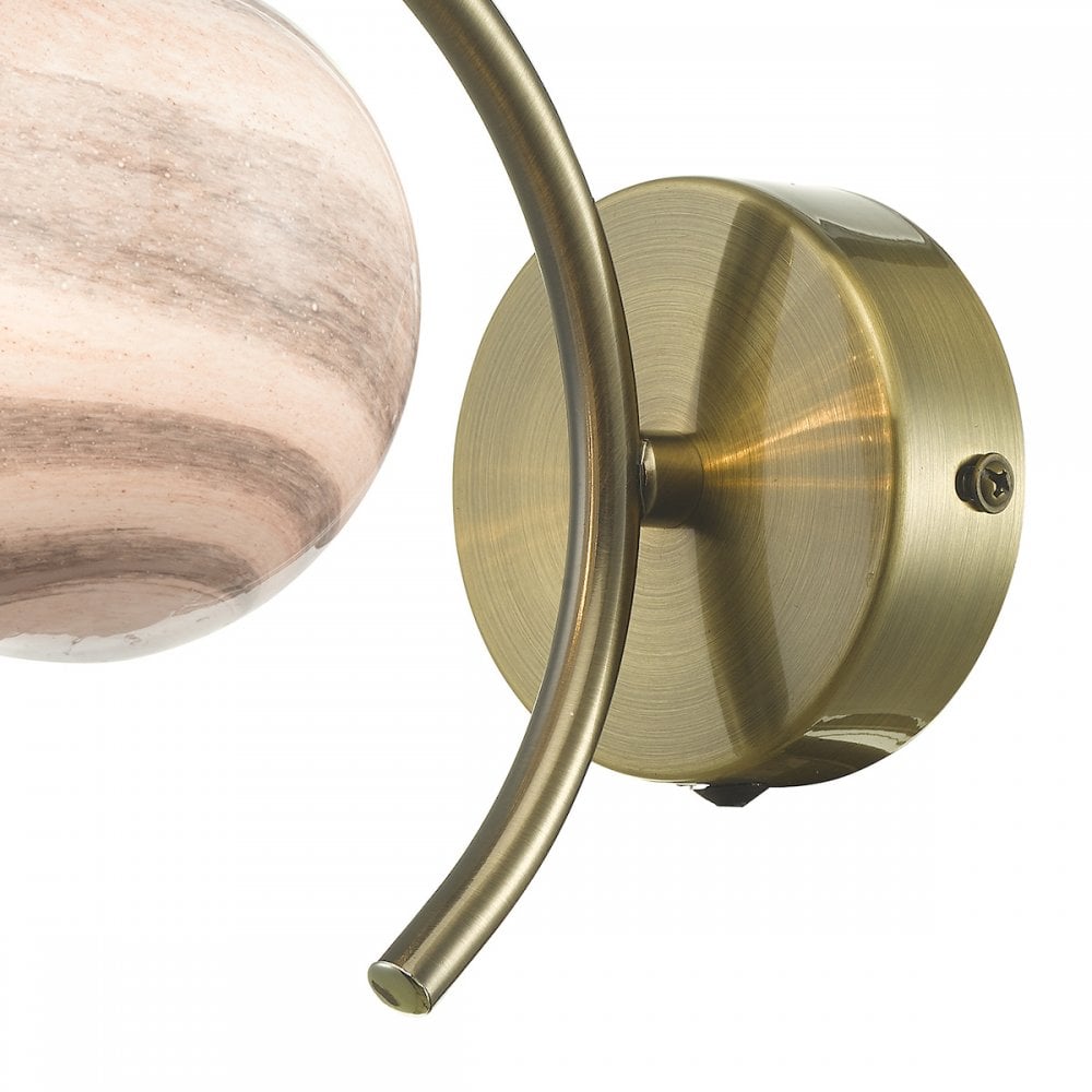 A close-up of the brass base and curved arm of the wall light.
