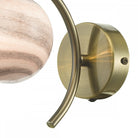 A close-up of the brass base and curved arm of the wall light.