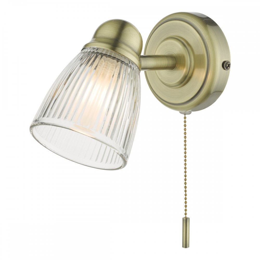 A brass wall light with a fluted glass shade and a pull cord switch.