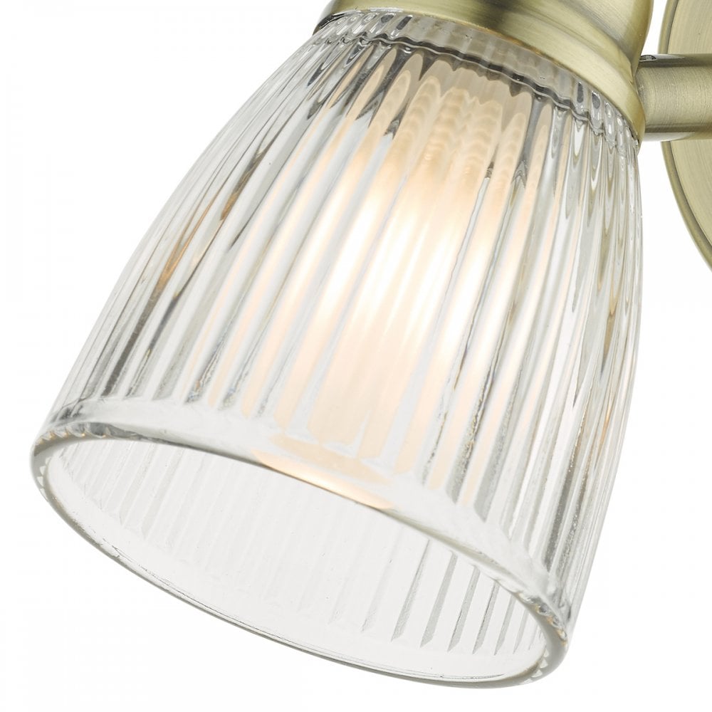 A close-up of a fluted glass shade on a brass wall light, showing the bulb inside.