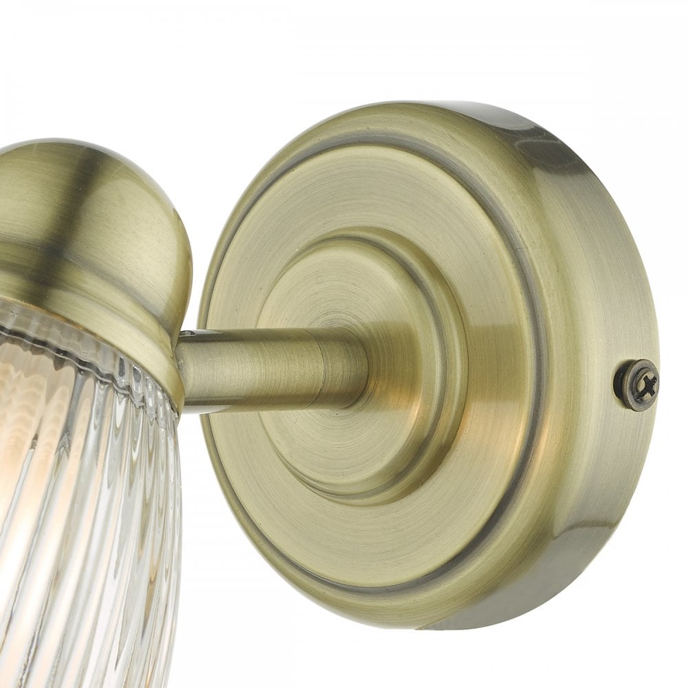 A close-up of the brass wall mount of a light fixture, showcasing its texture.