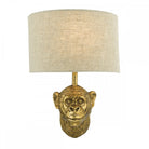 Golden monkey head wall light with a neutral linen shade.