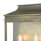 A close-up of the top and bulbs of a brass outdoor wall lantern.