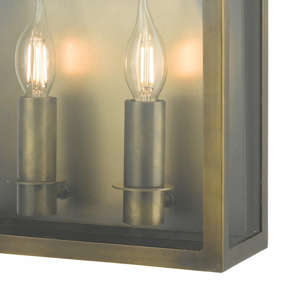 A close-up of the lit, candle-style bulbs inside the glass casing of a brass lantern.