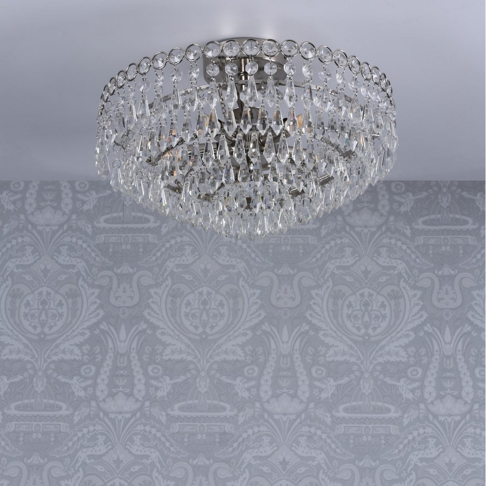 Crystal chandelier on a patterned grey ceiling, viewed from a low angle.