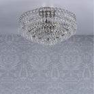Crystal chandelier on a patterned grey ceiling, viewed from a low angle.