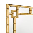 Detailed view of the top corner of a gold bamboo framed mirror.