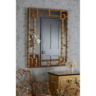 Gold bamboo mirror above a gold cabinet with a decorative gold chair nearby.