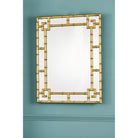 Gold bamboo mirror mounted on a teal wall.