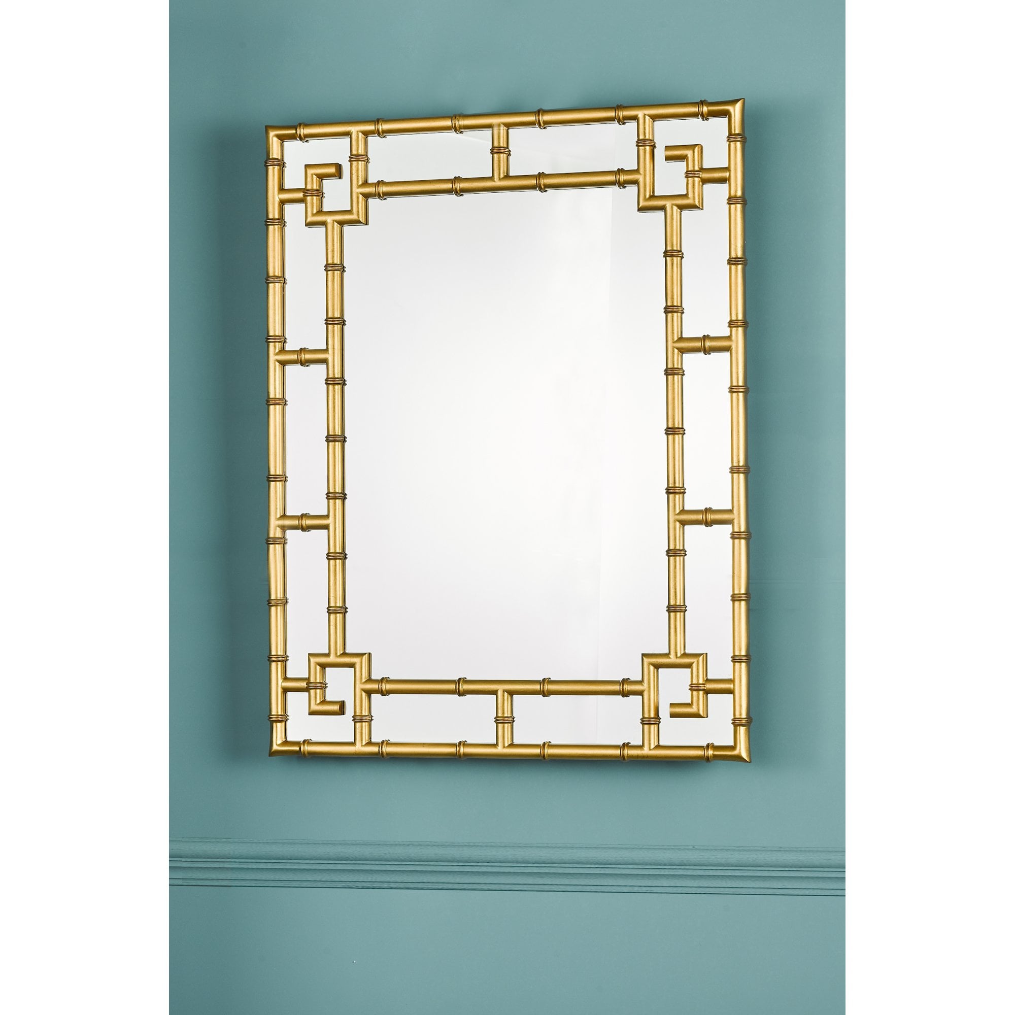 Gold bamboo mirror mounted on a teal wall.