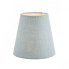 A small light blue fabric lamp shade with a warm glow from within, for ambient lighting.