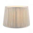 Pleated soft grey lamp shade with light on, showing the internal bulb glow.