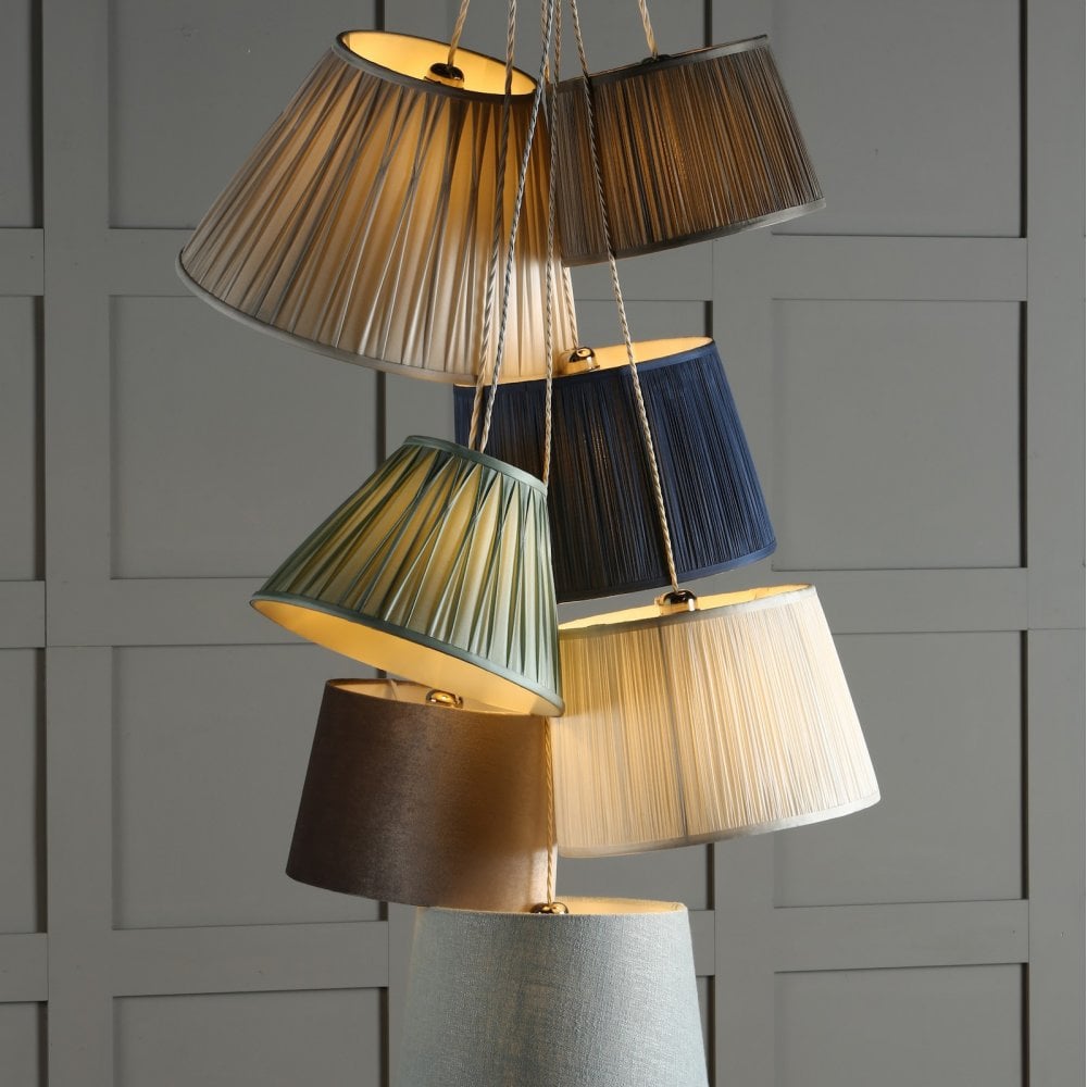 Multiple pleated lamp shades in various colours and sizes, stacked on top of each other.