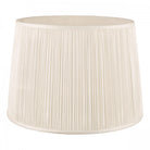 A pleated natural linen empire drum lampshade on a white background.
