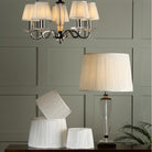 A pleated lampshade on a table lamp with matching lampshades on a chandelier.