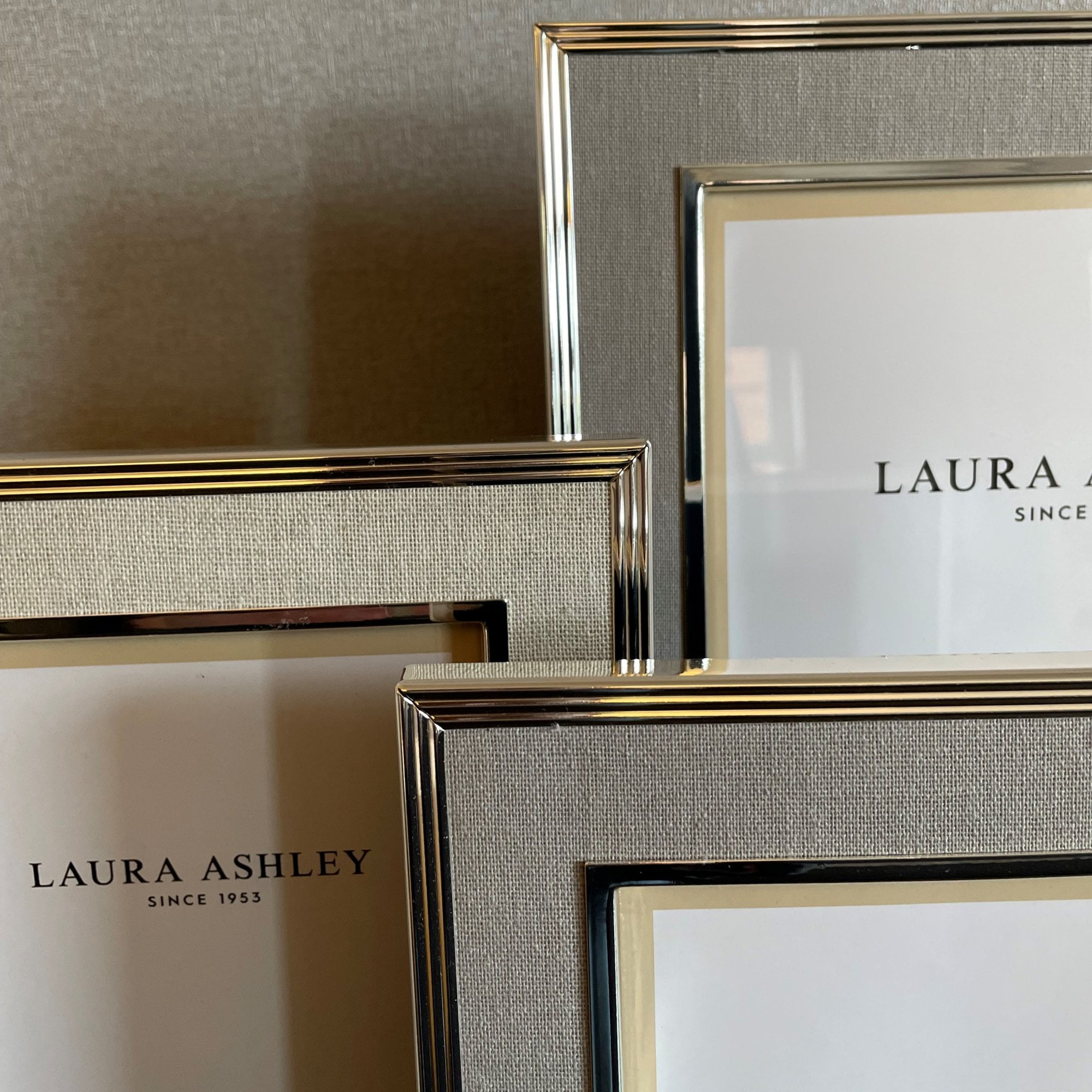 A collection of champagne-colored Laura Ashley photo frames in various sizes.