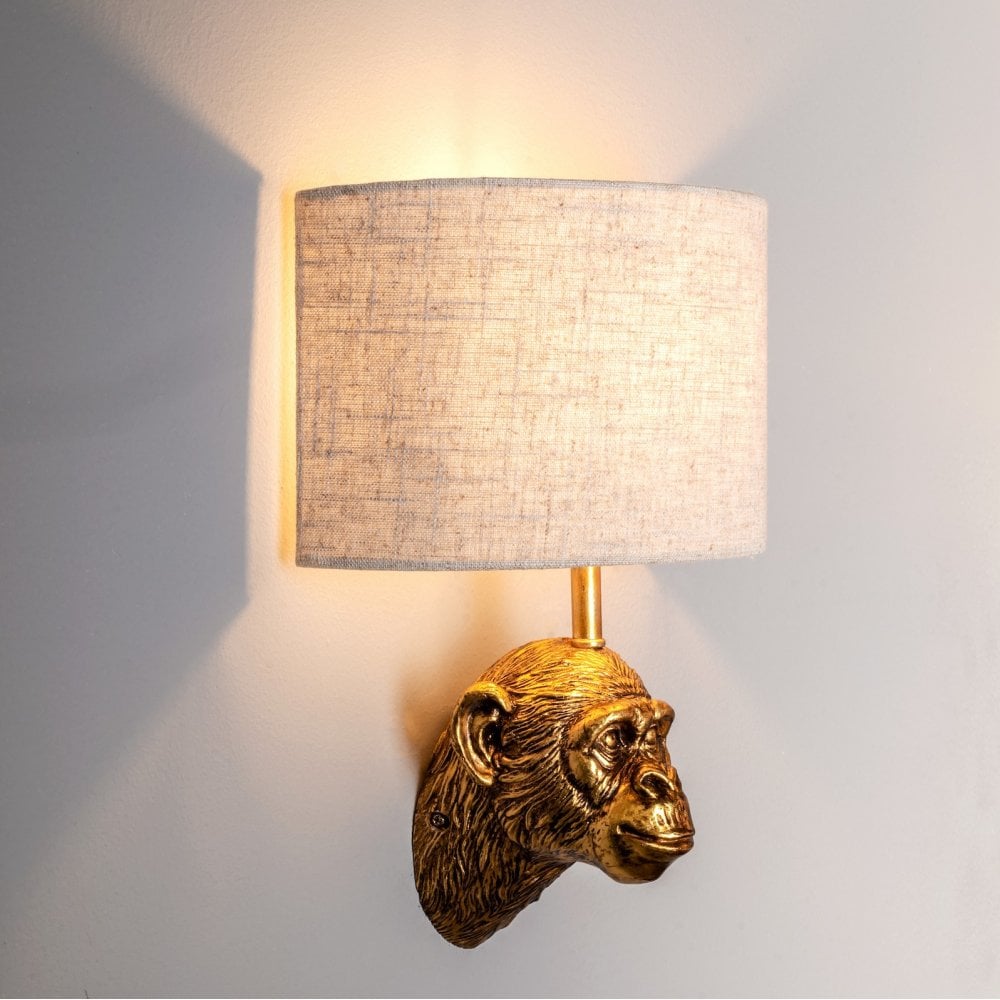 Golden monkey head wall light illuminating a textured wall.