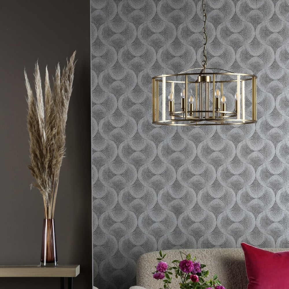 A brass chandelier hanging in a modern living room with patterned wallpaper.