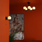 A ceiling light and a wall light with white spherical shades in a room with orange walls.