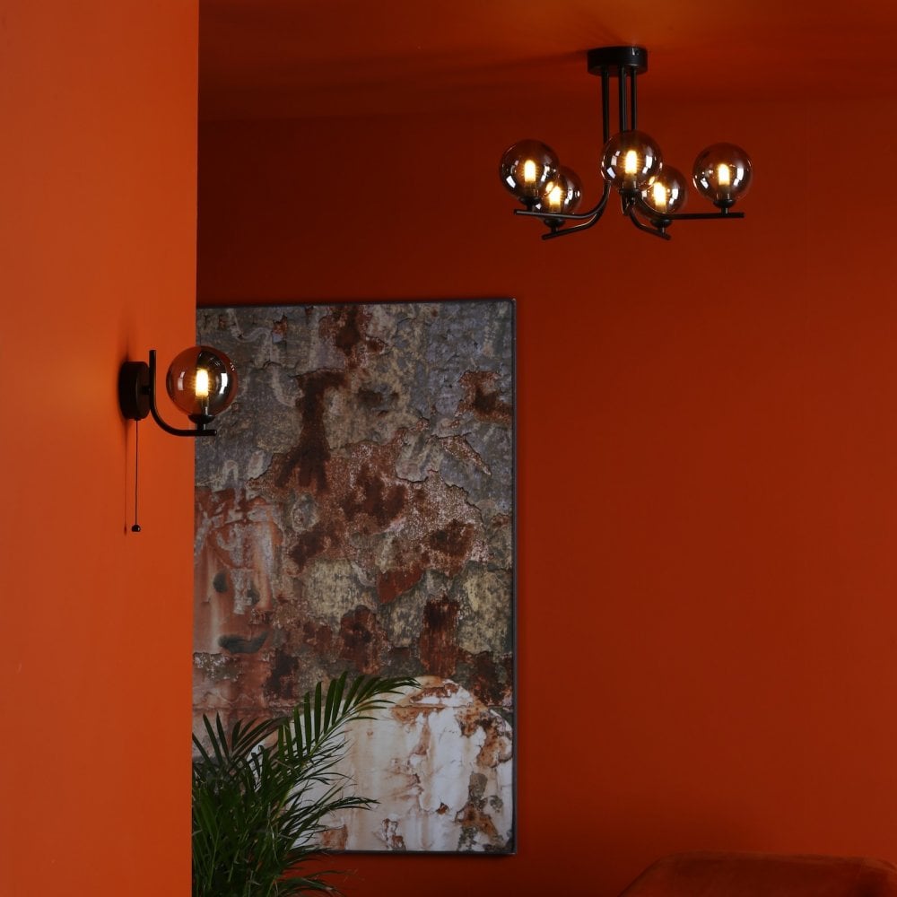 An orange room featuring a black ceiling chandelier and a matching wall light.