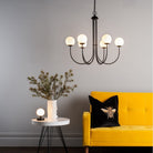 A modern living room with a yellow sofa, a spherical table lamp, and a chandelier.