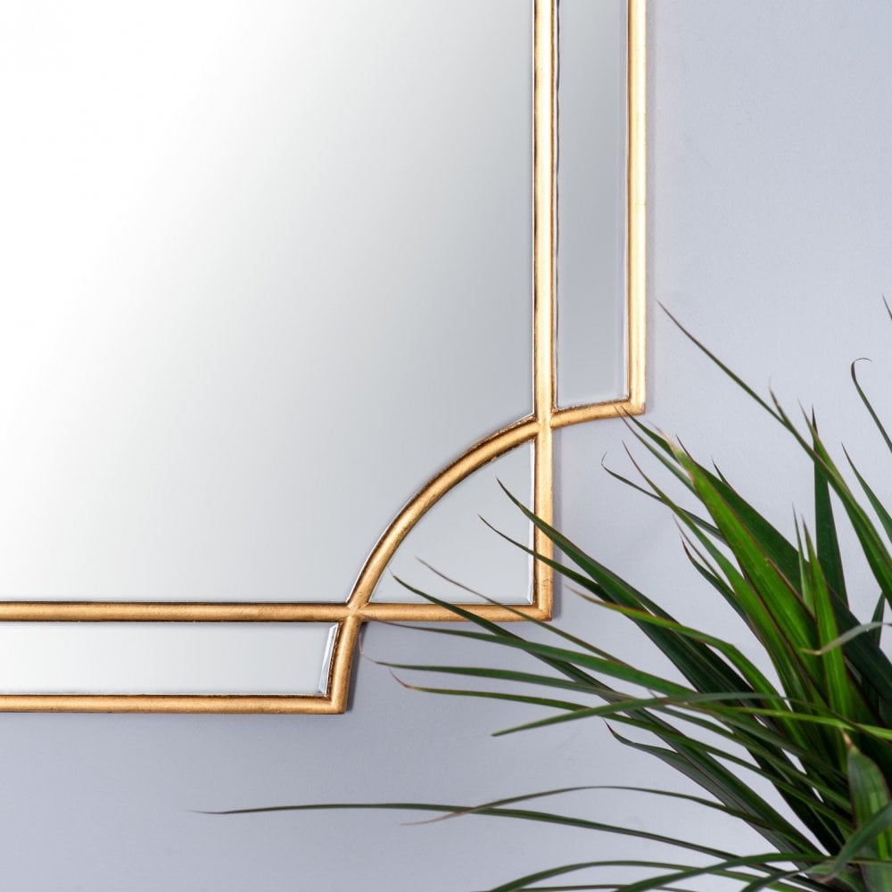 A close-up view of the ornate gold frame and curved details of the mirror.
