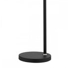 Detail of the round black base and slender pole of a modern table lamp.