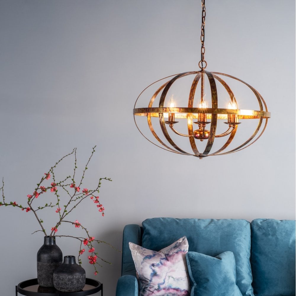 An orb chandelier illuminates a modern living room with a blue velvet sofa and minimalist decor.