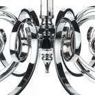 Close-up of the center of a silver chandelier with decorative, swirling arms.
