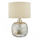 A mercury glass table lamp with a silver base and a white fabric drum shade.