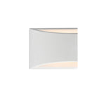 A close-up of a white wall sconce, showing light glowing from its top and bottom edges.