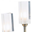 Close up of two clear rectangular shades with bulbs in an antique brass wall light.
