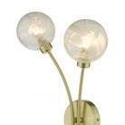 Close-up of a modern double wall light with two clear glass orb shades and a brass base.