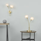 A brass wall light and matching table lamp with spherical glass shades illuminate a room.
